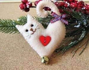 a white cat ornament with a red heart hanging from it's back