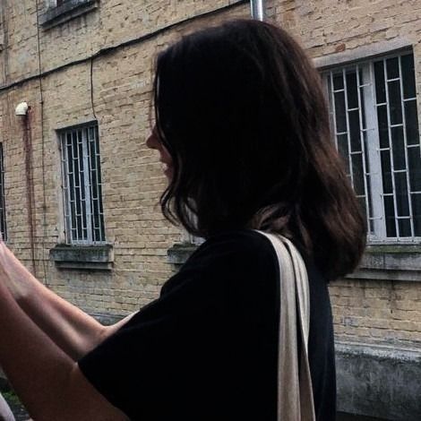 a woman standing outside looking out the window at an animal that is eating from her hand