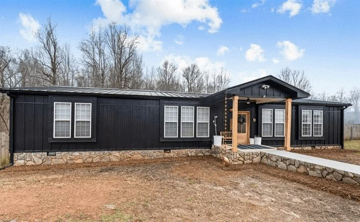 a black house sitting on top of a dirt field