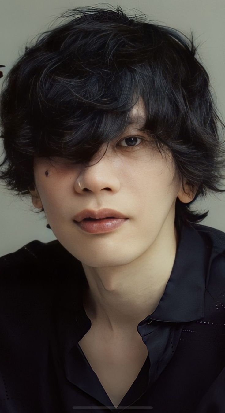 a young man with black hair is looking at the camera while wearing a black shirt