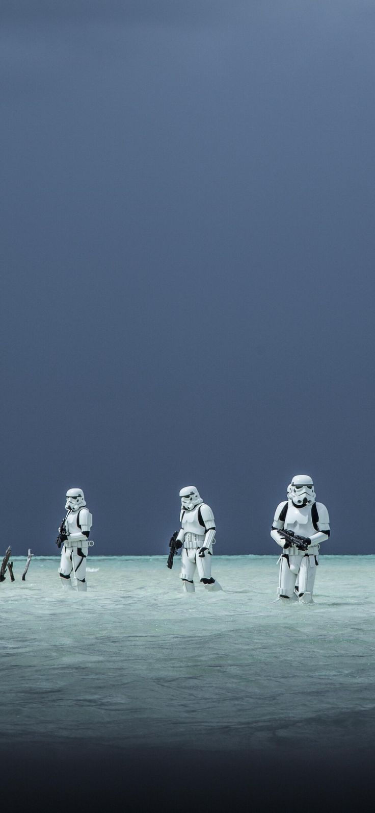 four stormtroopers walking in the water under a dark sky with birds flying by