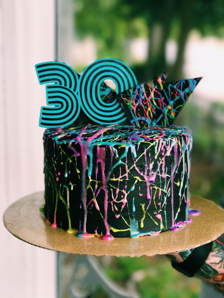 a decorated birthday cake with the number 30 on it and splattered icing