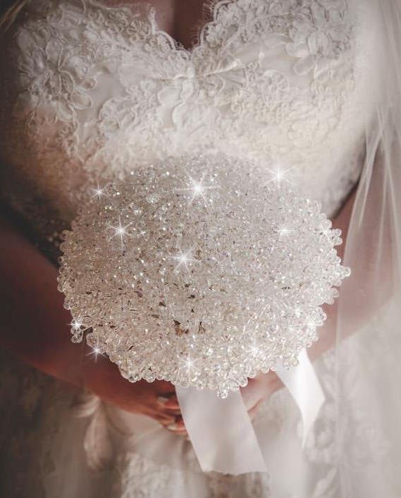 the bride is holding her wedding bouquet with pearls and sequins on it's back