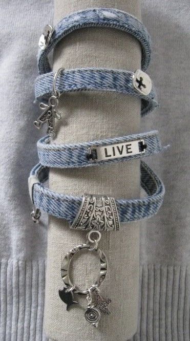 a stack of bracelets on top of a white cloth covered napkin with charms attached to it