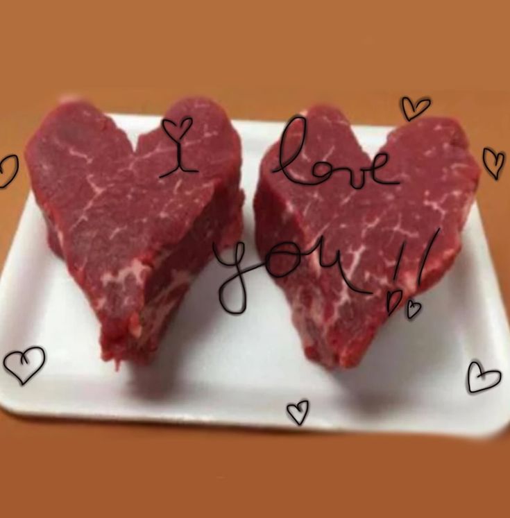 two pieces of heart shaped meat on a plate with the words i love you written above them