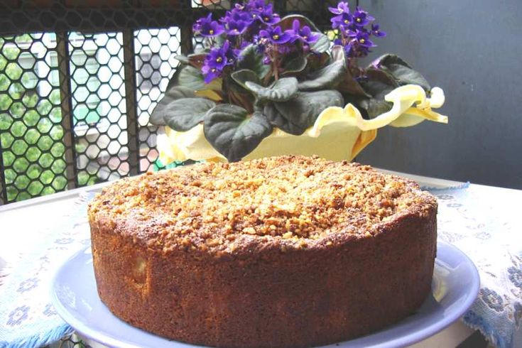 a cake sitting on top of a white plate next to a potted purple plant