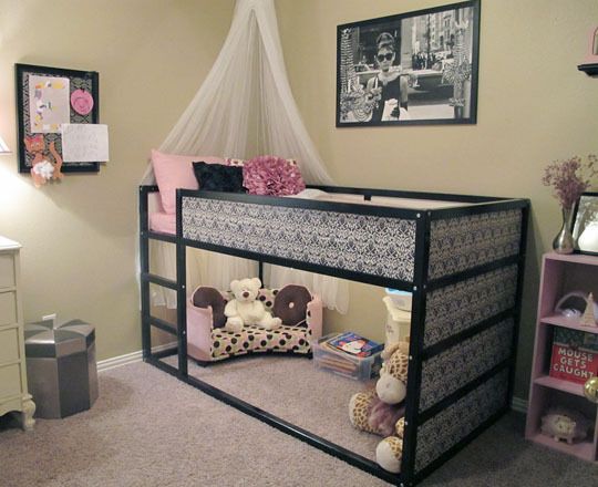 a child's bunk bed with stuffed animals on the bottom, and other furniture in the background