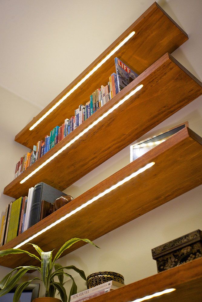 bookshelves with wooden shelves and plants on them in the corner of a room