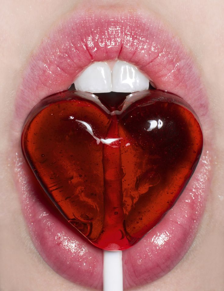 a red heart shaped lollipop sticking out of the lip