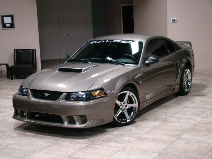 a silver sports car parked in a room with tile flooring and gray walls on the wall