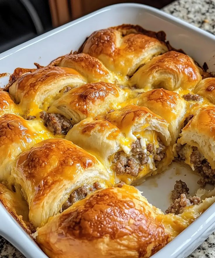 a casserole filled with meat and cheese in a white dish on top of a granite counter