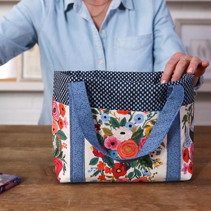 a woman is holding a floral bag on the table