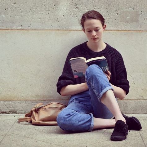 a woman sitting on the ground reading a book