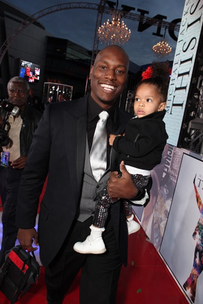 a man in a suit and tie holding a child on the red carpet at an event