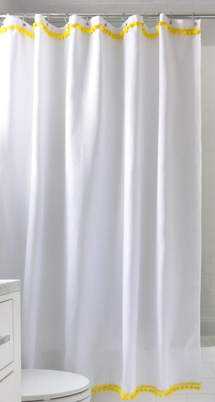 a white shower curtain with yellow trim in a bathroom