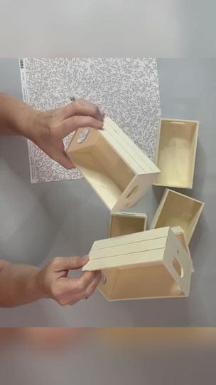 two hands holding open boxes on top of each other in front of a white wall