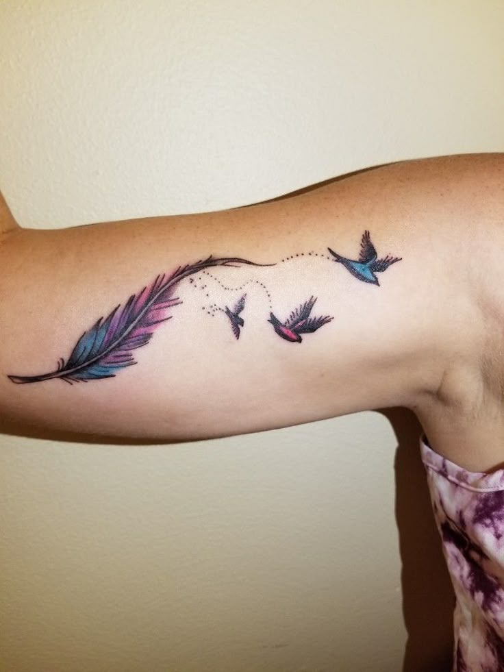 a woman with a tattoo on her arm that has birds flying in the sky and arrows coming out of it