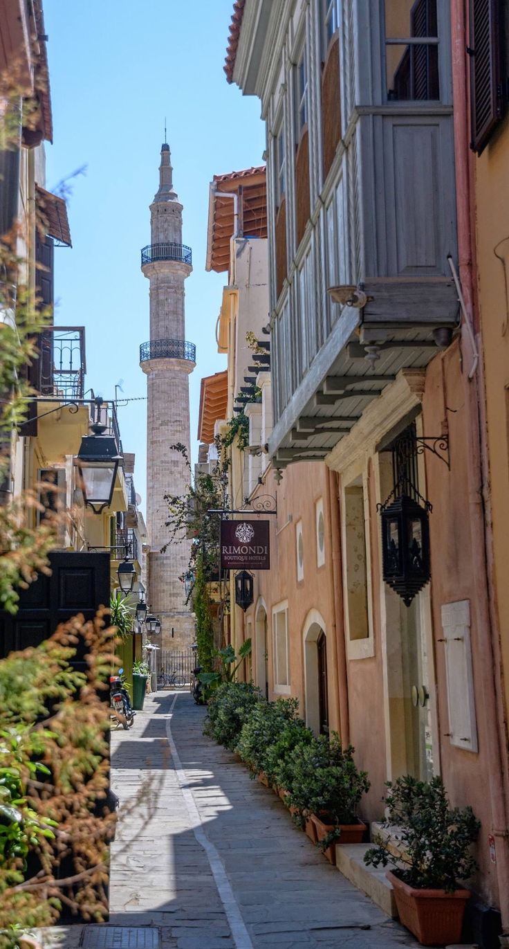 an alley way with buildings and a clock tower in the background