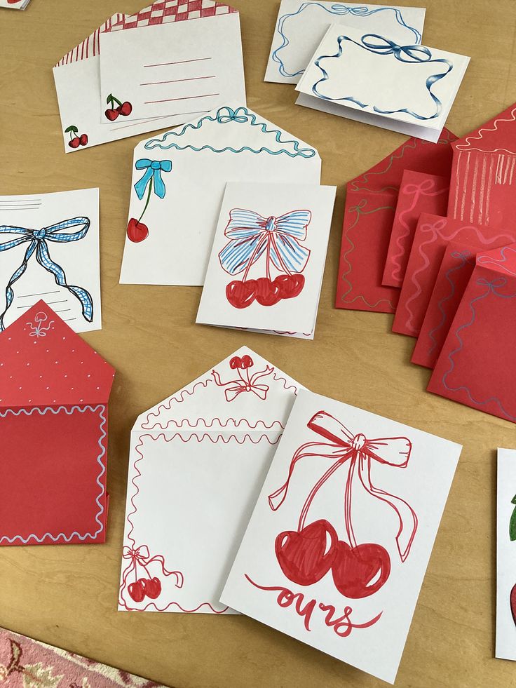 several cards and envelopes with designs on them sitting on a wooden table next to each other