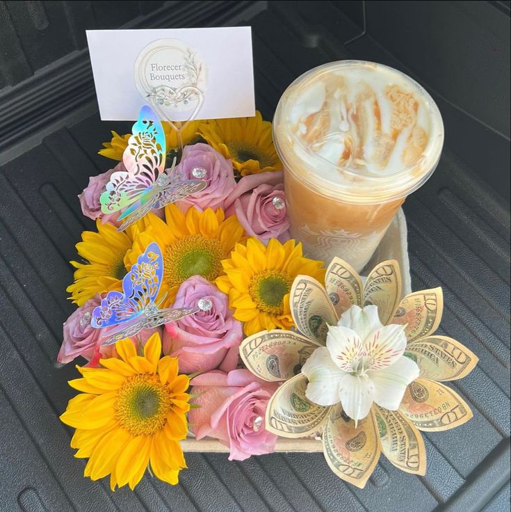 a cup of coffee sitting on top of a table next to some flowers and butterflies