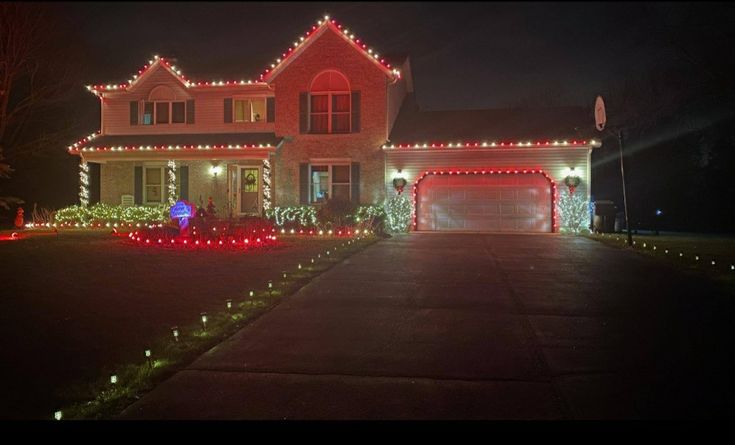 a house with christmas lights on it's front yard and driveway in the evening