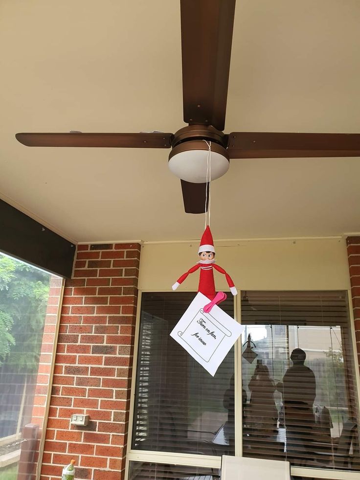 an elf is hanging from the ceiling in front of a window