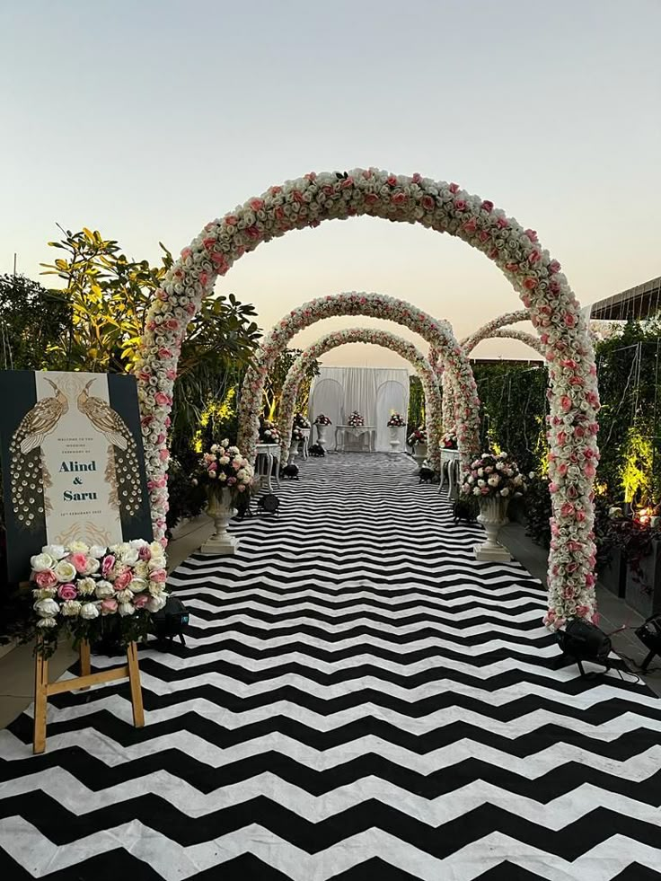 a black and white chevroned carpet with flowers on the floor, an arch decorated with roses