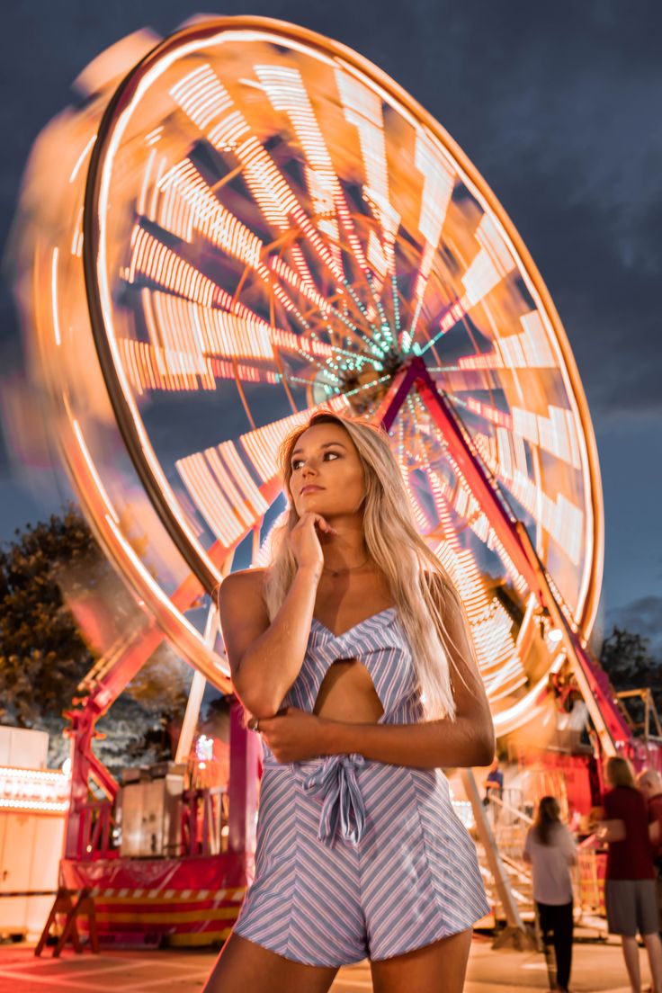 a woman standing in front of a ferris wheel