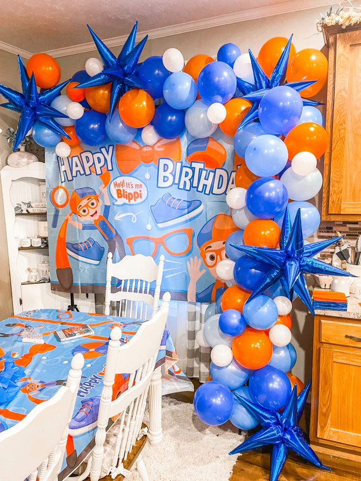 a birthday party decorated with balloons and blue, orange and white stars on the wall