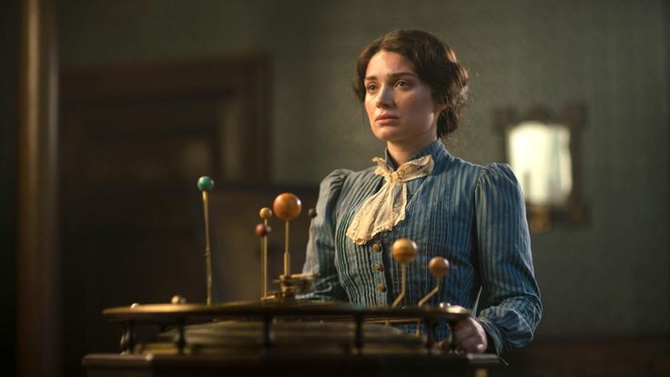 a woman standing in front of a table with wooden balls on it