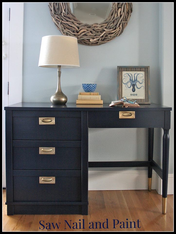 a black desk with two drawers and a mirror on the wall in front of it