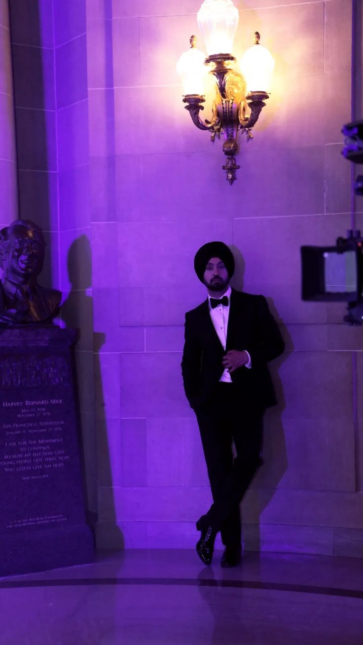 a man in a tuxedo standing next to a purple light