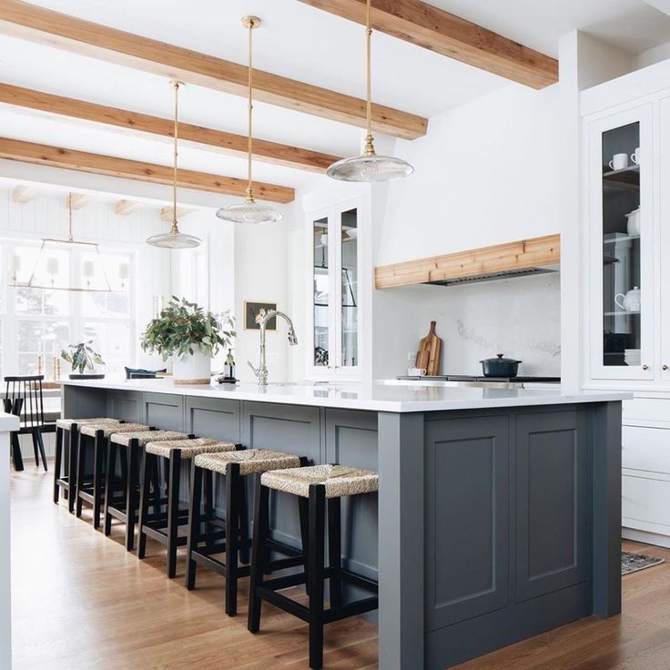 a large kitchen with an island and bar stools in the center, along with wooden floors