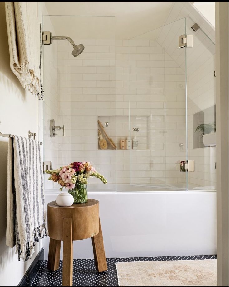 a white bath tub sitting next to a wooden stool with flowers on top of it