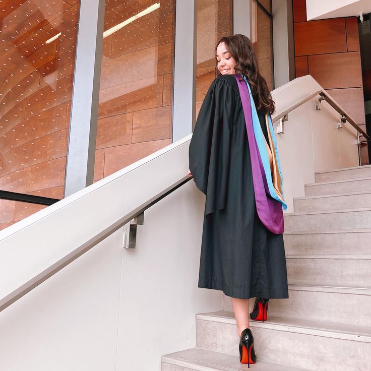 a woman in a graduation gown is standing on the stairs