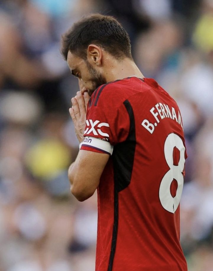 a soccer player with his hands clasped to his face while standing in front of an audience