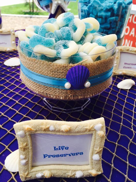 a table topped with a bowl filled with blue and white candy next to a sign