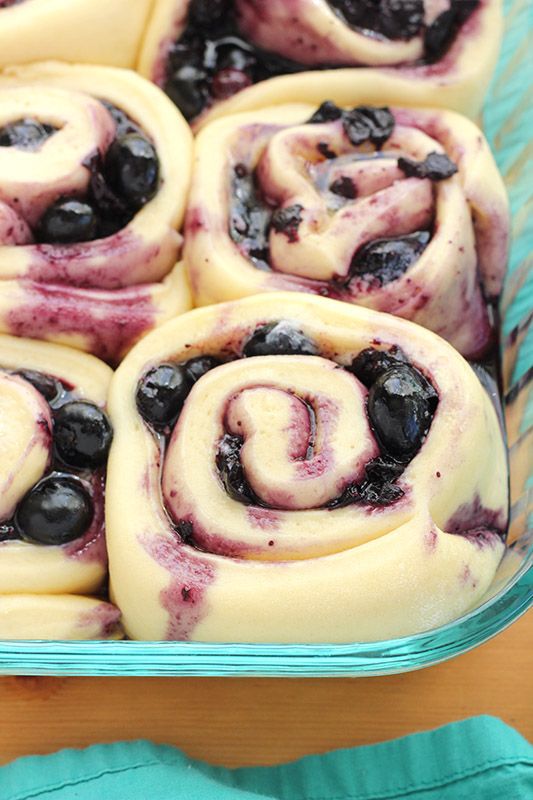 blueberry swirl rolls in a glass dish on a wooden table with green napkins