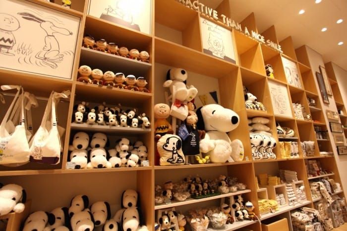 many stuffed animals are on shelves in a room with wooden shelvings and lights