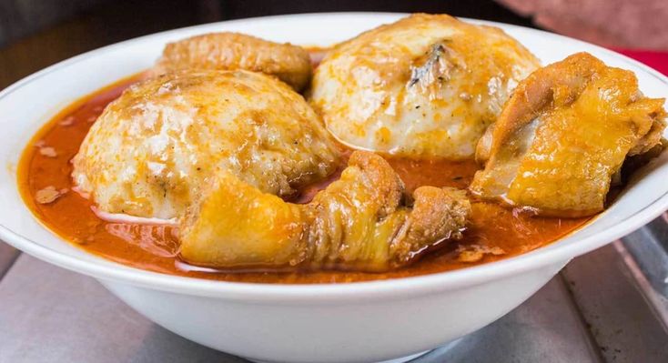 a white bowl filled with meat covered in sauce