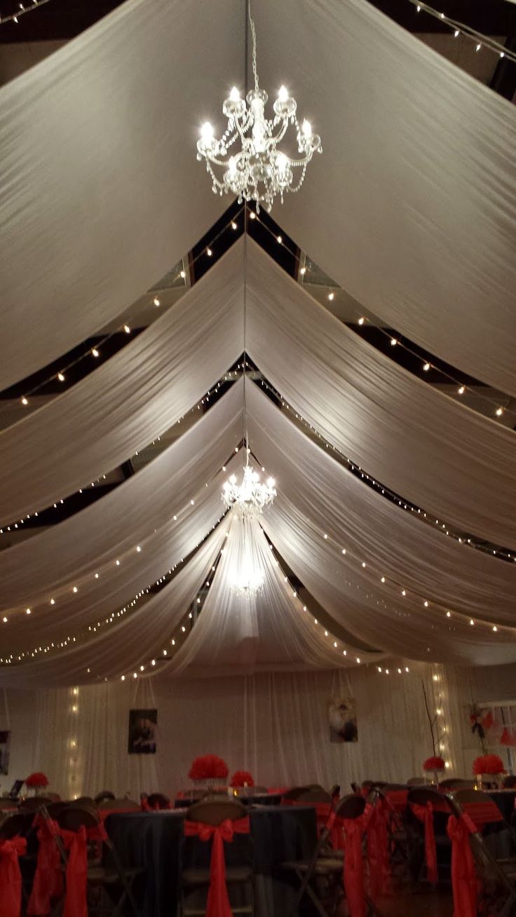 the inside of a tent decorated with red bows and lights for an elegant wedding reception