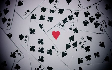 playing cards with red heart surrounded by black and white spades, all on one side