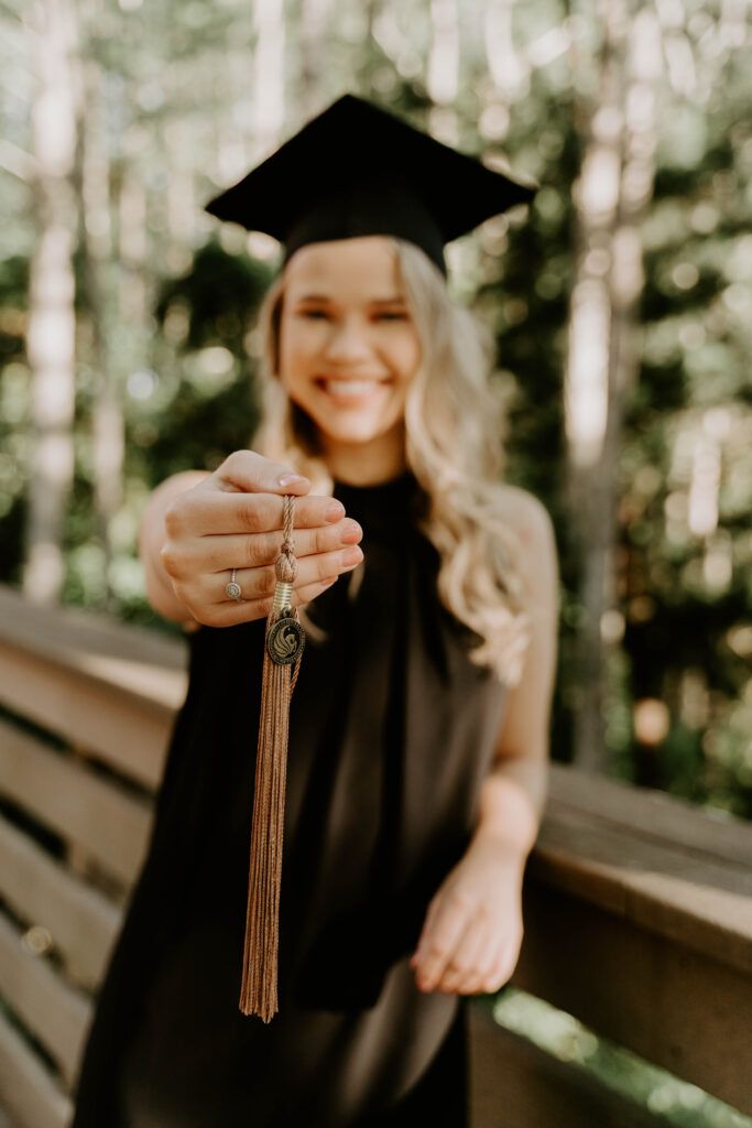 a woman wearing a graduation cap and gown is holding a tassel in her hand