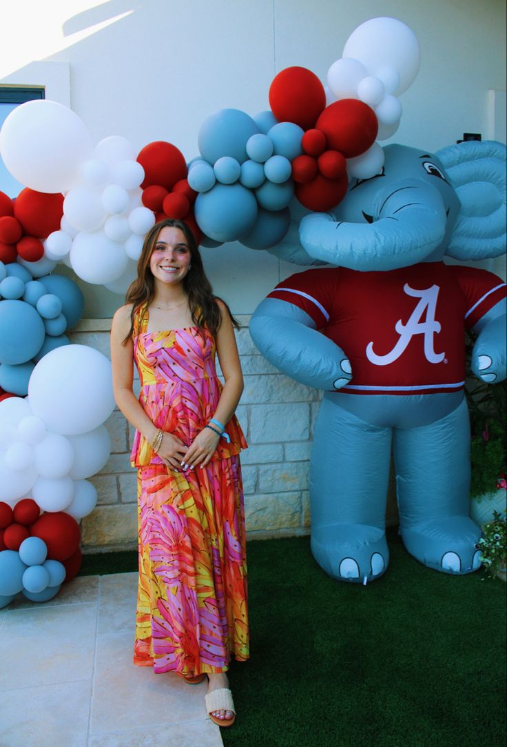 a woman standing in front of an elephant balloon arch