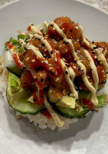 a white plate topped with rice covered in sauce and cucumber slices on top of it