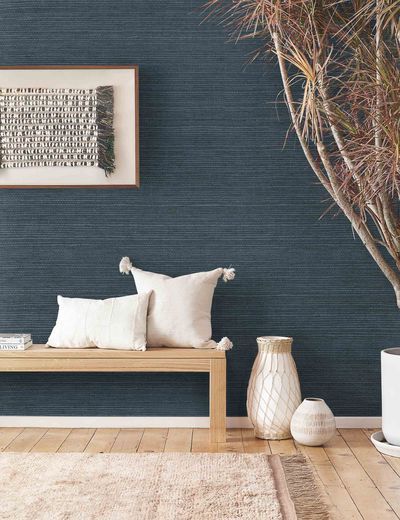 a wooden bench sitting in front of a blue wall next to a vase filled with flowers