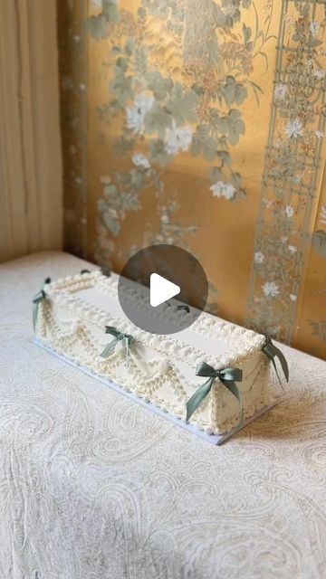 a cake sitting on top of a bed in front of a wallpapered room