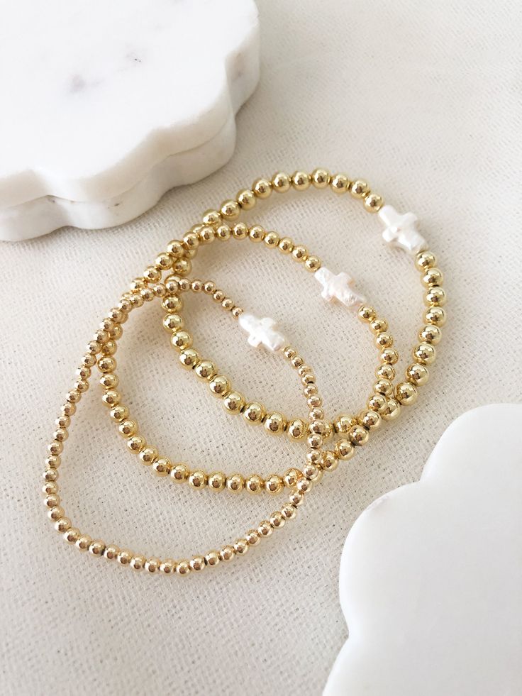 ☞ Features  ✤ Dainty, and beautiful cross shaped freshwater pearl on a 14k gold layered beaded bracelets. ✤ Choose your bead size and adjust it to your wrist in the drop- box.  ✤ The beads are made of a thick and sturdy 18k gold plated material.  ✤ Gently Handmade and Polished  ☞ Shipping ✤ Packages are sent out in 1-2 days after orders are placed from Monday through Saturday. ✤ All orders come ready to gift in our beautiful packaging. ✤ I have tried to design our packaging to be as sustainable Dainty Gold Beaded Bracelet, Dainty Gold Beaded Bracelets, Gold Stretch Bracelet With Tiny Beads For Gift, Delicate Adjustable Gold Beads Bracelet, Delicate Beaded 14k Gold-filled Bracelets, Dainty Gold Beaded Bracelets With Tiny Beads, Dainty Hand-strung Gold Beaded Bracelets, Dainty Gold Beaded Rosary Bracelet, Gold Rosary Bracelet With Tiny Beads Gift