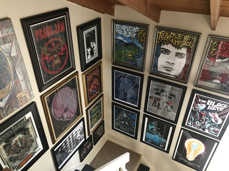 there are many framed pictures on the wall in this room with stairs leading up to it