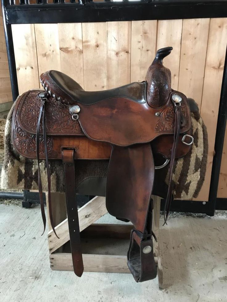 a brown saddle sitting on top of a wooden stand